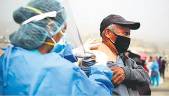 CURA. Una enfermera aplica una inyección sobre un ciudadano peruano con mascarilla.
