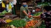 EN FILIPINAS. Un proveedor atiende a una cliente en un mercado, donde el uso de mascarilla y protectores es obligatorio en Taytay, provincia de Rizal.