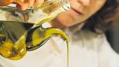 ORO LÍQUIDO. Una mujer empapa una tostada con aceite de oliva.