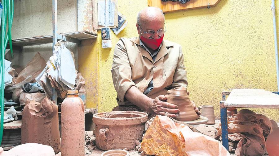 <i>DE MEMORIA. Paco Sáez moldea barro en el torno de su taller en “La Casa del Artesano”.</i>