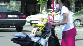 PASEO. Una madre empuja el carrito de su bebé por las calles de la capital y detrás, otro progenitor con su niño.