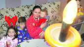 FELICIDAD. María Donaire, con sus tres hijos, sentados en el sofá y con la luz encendida.
