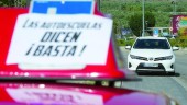 PRÁCTICAS. Dos coches de autoescuela durante unas clases, con carteles en contra de los paros. (Emilio Arroyo) 
