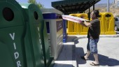 RESIDUOS. Un hombre tira un embalaje de cartón en un contenedor azul del punto limpio.