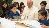 CASA DE SANTA MARTA. El Papa observa un cuento con el que fue obsequiado por los pequeños refugiados.