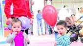 infantil. Una niña y un niño miran a la cámara con sus piruletas y globos en la feria “Piccolo mundo”.