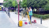 ACTIVIDAD. Un topógrafo realiza mediciones en la Plaza Deán Mazas. En segundo plano, vecinos concentrados en contra de las obras y camiones de reparto. 