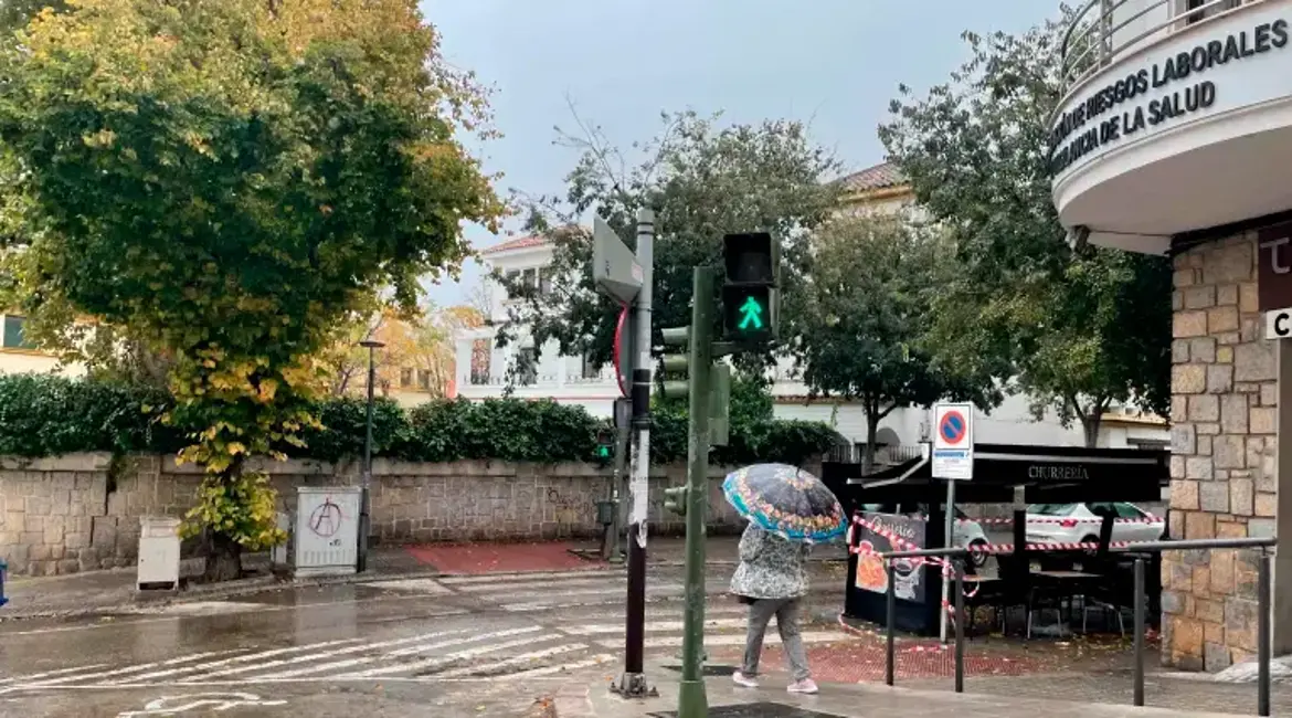 Una mujer con paraguas pasea por el cruce entre las calles Puerta del Sol y Arquitecto Berges. / Diario JAÉN.