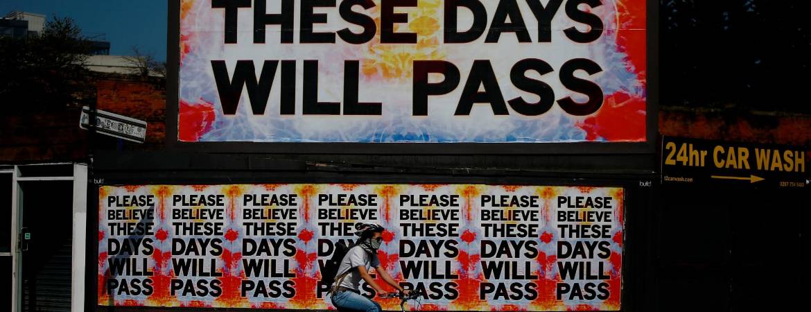 EN LONDRES. Una persona pasa con su bicicleta junto a una valla publicitaria con el mensaje “ Por favor, cree en que estos días pasarán”. La foto fue tomada en Shoreditch, una zona del barrio londinense de Hoxton.