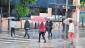 LLUVIA. Ciudadanos cruzan un paso de cebra en la capital jiennense con el paraguas de la mano.