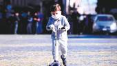 EN ITALIA. Un niño con mascarilla en su rostro como medida de protección monta en su patinete por la calle. 