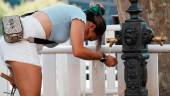 Una mujer bebe agua de una fuente durante la cuarta ola de calor del verano. / H. Bilbao / Europa Press.