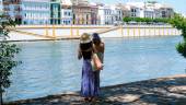 Personas con ropa veraniega paseando junto al río Guadalquivir, en Sevilla. / María José López / Europa Press.