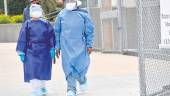 EN NUEVA YORK. Dos sanitarios protegidos con pantallas, marcarillas y un traje impermeable salen del hospital.