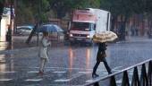 Dos mujeres cruzan bajo un paraguas un paso de peatones tras las fuertes lluvias. Archivo. / Joaquín Corchero / Europa Press.