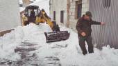 Vecinos de La Matea (Santiago-Pontones), uno de ellos con una excavadora, tratan de retirar la nieve acumulada en las calles de la aldea.