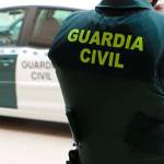 Un agente de la Guardia Civil, de espaldas, junto a un vehículo oficial. Archivo.