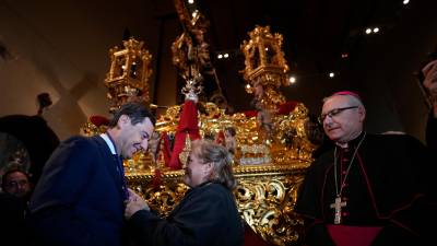 La Hermana Mayor de la Cofradía, Rosa Garrido, entrega la medalla de Nuestro Padre Jesús a Juanma Moreno. / Junta de Andalucía.
