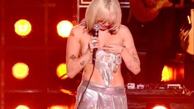 Miley Cyrus se sujeta el top al darse cuenta de que se le había desabrochado.
