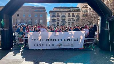 Los participantes sujetan una pancarta de la asociación “Tejiendo Puentes” instantes previos a la carrera. / Álvaro Guzguti.