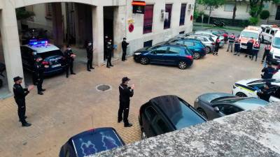 Agentes de la Policía Nacional aplauden fuera de una conmisaría con las sirenas de sus coches activadas.