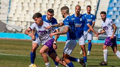 David Serrano se abre paso entre dos jugadores de la UD Melilla. / UD Melilla.