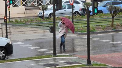 Una viandante se protege de las lluvias y el viento durante esta semana.
