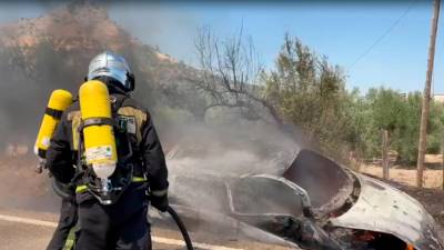 Un bombero apaga el fuego del coche tras el accidente. / Ayuntamiento de Jaén. 