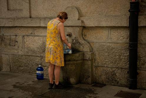 <i>Una persona rellena botellas de agua en una fuente pública. / Europa Press. </i>