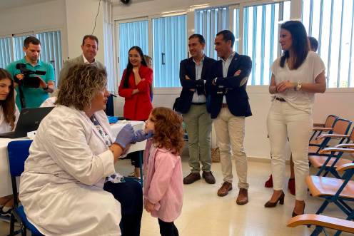 <i>Una profesional sanitaria administra la vacuna antigripal intranasal a una alumna en el CEIP Ángel López Salazar de Baeza, bajo la mirada de los delegados de Sanidad, Lucía Mónica Pérez Nava, y de Educación, Francisco José Solano. / Junta de Andalucía. </i>