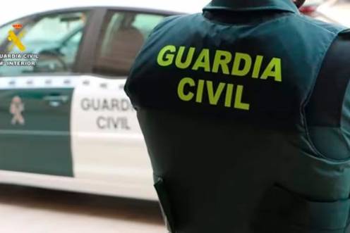 <i>Un agente de la Guardia Civil junto a un vehículo oficial. / Guardia Civil.</i>