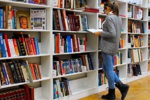 <i>Una mujer ojeando libros en una biblioteca. / Junta de Andalucía. </i>
