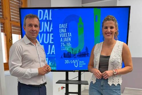<i>Julio Millán y Beatriz López posan delante del cartel de la Media Maratón de Jaén, que cumple su trigésima edición. / Ayuntamiento de Jaén. </i>