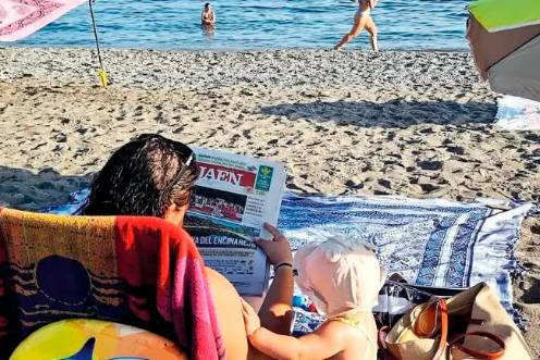 <i>Una mujer ojea la portada de Diario JAÉN en la playa, ante la curiosidad de su bebé. / Diario JAÉN.</i>