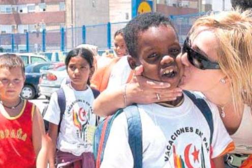 <i>Una madre de acogida le ofrece a una niña un zumo y comida mientras se produce el reparto de los niños con sus familias. / Archivo Histórico de Diario JAÉN.</i>