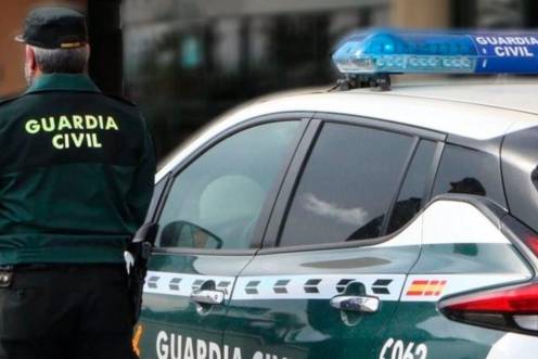 <i>Un agente de la Guardia Civil, de espaldas, junto a un vehículo oficial. Archivo. / Guardia Civil.</i>