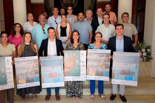<i>Autoridades locales y organizadores, posa para una fotografía promocional en la escalera interior de un edificio institucional para presentar la III Feria de la Perdiz de La Carolina. / Junta de Andalucía. </i>