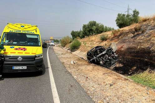 <i>La ambulancia del Emergencias 061, junto al vehículo calcinado en la N-322 de Linares. / Diario JAÉN.</i>