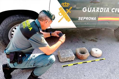 <i>Un agente de la Guardia Civil fotografía los tres objetos. / Guardia Civil.</i>