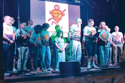 <i>Alejandro Castillo lee su pregón desde el escenario arropado por miembros del Club Aspergianos Jaén, durante el arranque de las fiestas en honor a San Cosme y San Damián en Jabalcuz. / Adrián Claudio Bonache / Diario JAÉN. </i>