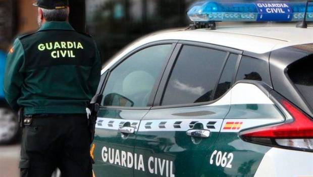 <i>Un agente de la Guardia Civil, de espaldas, junto a un vehículo oficial.</i>