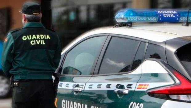 <i>Un agente de la Guardia Civil, de espaldas, junto a un vehículo oficial. Archivo. / Guardia Civil.</i>