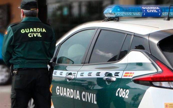 <i>Un agente de la Guardia Civil, de espaldas, junto a un vehículo oficial. Archivo.</i>