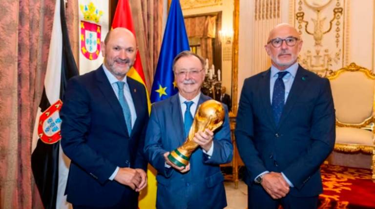 <i>El presidente de la RFEF, Rafael Louzán, el presidente de la Ciudad Autónoma de Ceuta, Juan Jesús Vivas, y el seleccionador nacional, Luis de la Fuente, junto a la Copa del Mundo en la sede del Gobierno de Ceuta. / RFEF. </i>