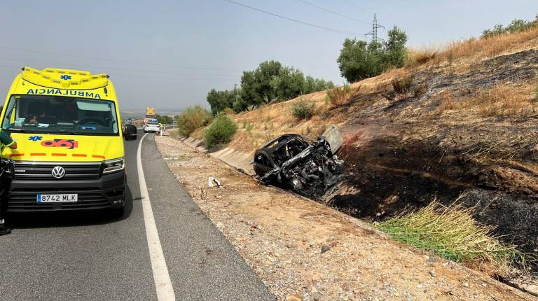 <i>La ambulancia del Emergencias 061, junto al vehículo calcinado en la N-322 de Linares. / Diario JAÉN.</i>
