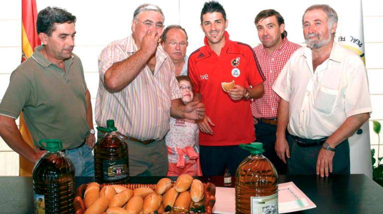 <i>David Villa con un bollo de pan con aceite que le entrega el alcalde de Villatorres. / Archivo histórico Diario JAÉN. </i>