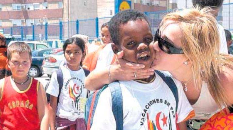 <i>Una madre de acogida le ofrece a una niña un zumo y comida mientras se produce el reparto de los niños con sus familias. / Archivo Histórico de Diario JAÉN.</i>