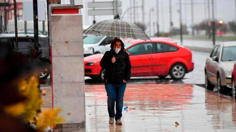 Una mujer se protege de la lluvia en Jaén capital.