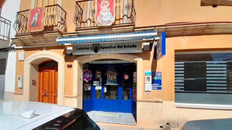 <i>Puerta de la administración ubicada en la calle Real, en Navas de San Juan, donde se ha vendido el número 33.478. / Loterías y Apuestas del Estado. </i>