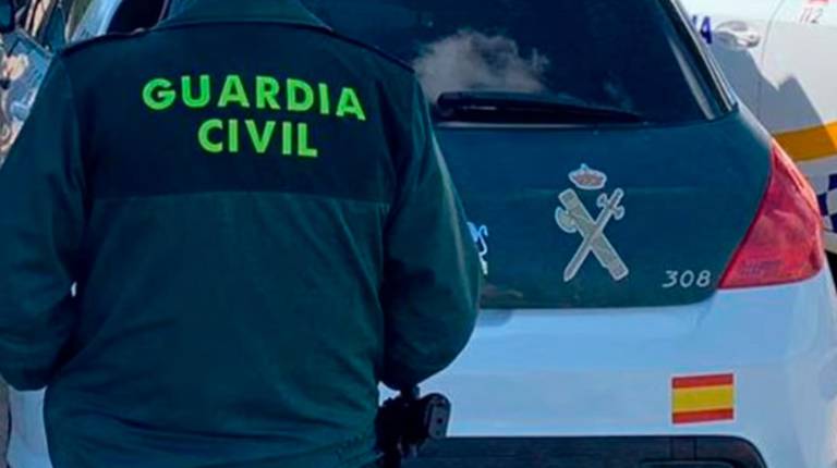 <i>Un agente de la Guardia Civil junto a un vehículo oficial. / Guardia Civil. </i>